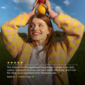 Woman in a pink and yellow checkered coat holding colorful balls with a scenic background