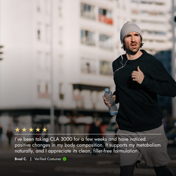 Man running outdoors with a water bottle, wearing a black jacket and gray beanie.